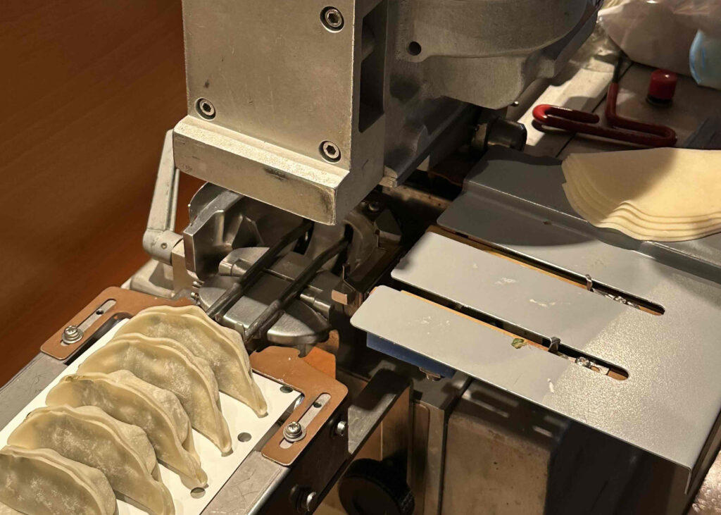 餃子を包む機械で牡蠣餃子を作る様子